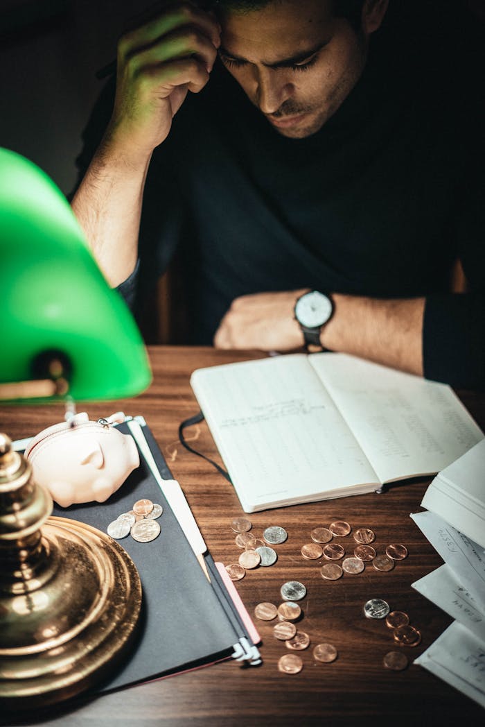 why-choose-us High angle of concentrated man at table with retro lamp and coins contemplating on notes in journal