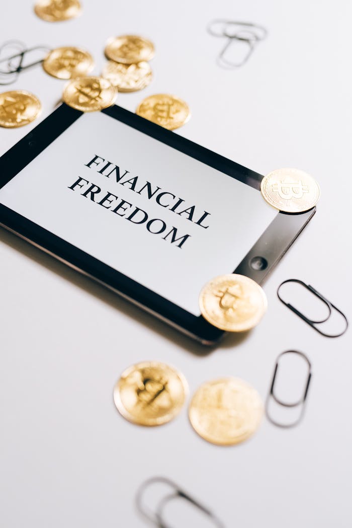 services-03 Coins are scattered around a digital tablet displaying 'Financial Freedom', symbolizing cryptocurrency wealth.